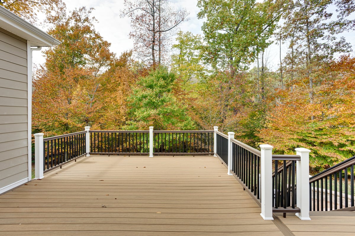 Cedar deck bordered by a simple railing, overlooking a forest of autumn trees
