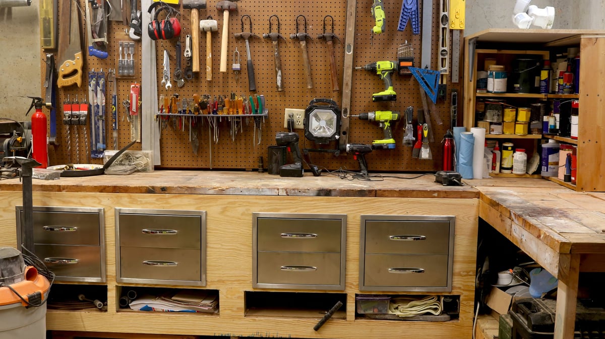 Homeowner's garage workshop with power tools and hand tools arranged on shelves and a workbench